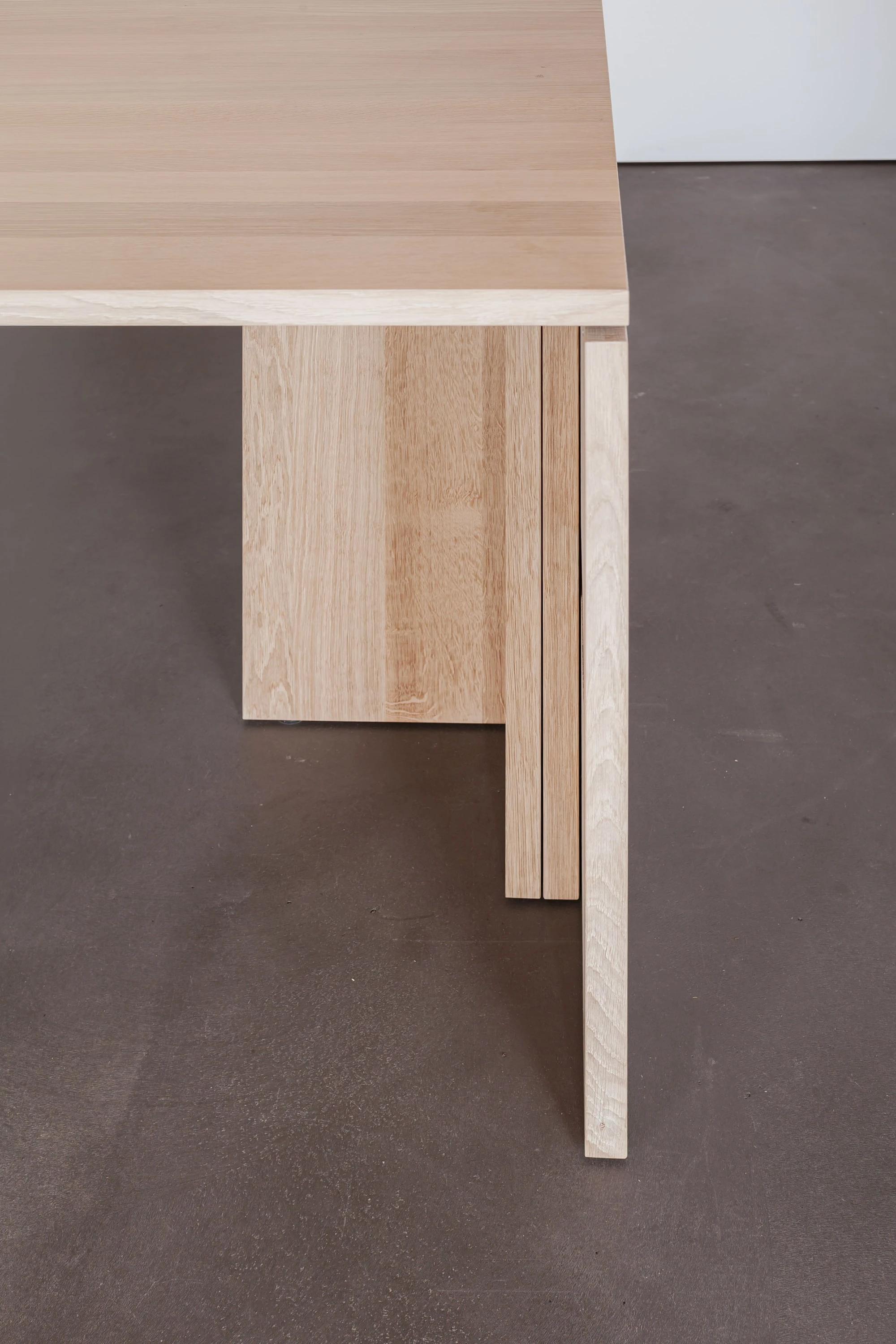 Tischecke mit Plattenfuss aus Holz in der Seitenansicht.