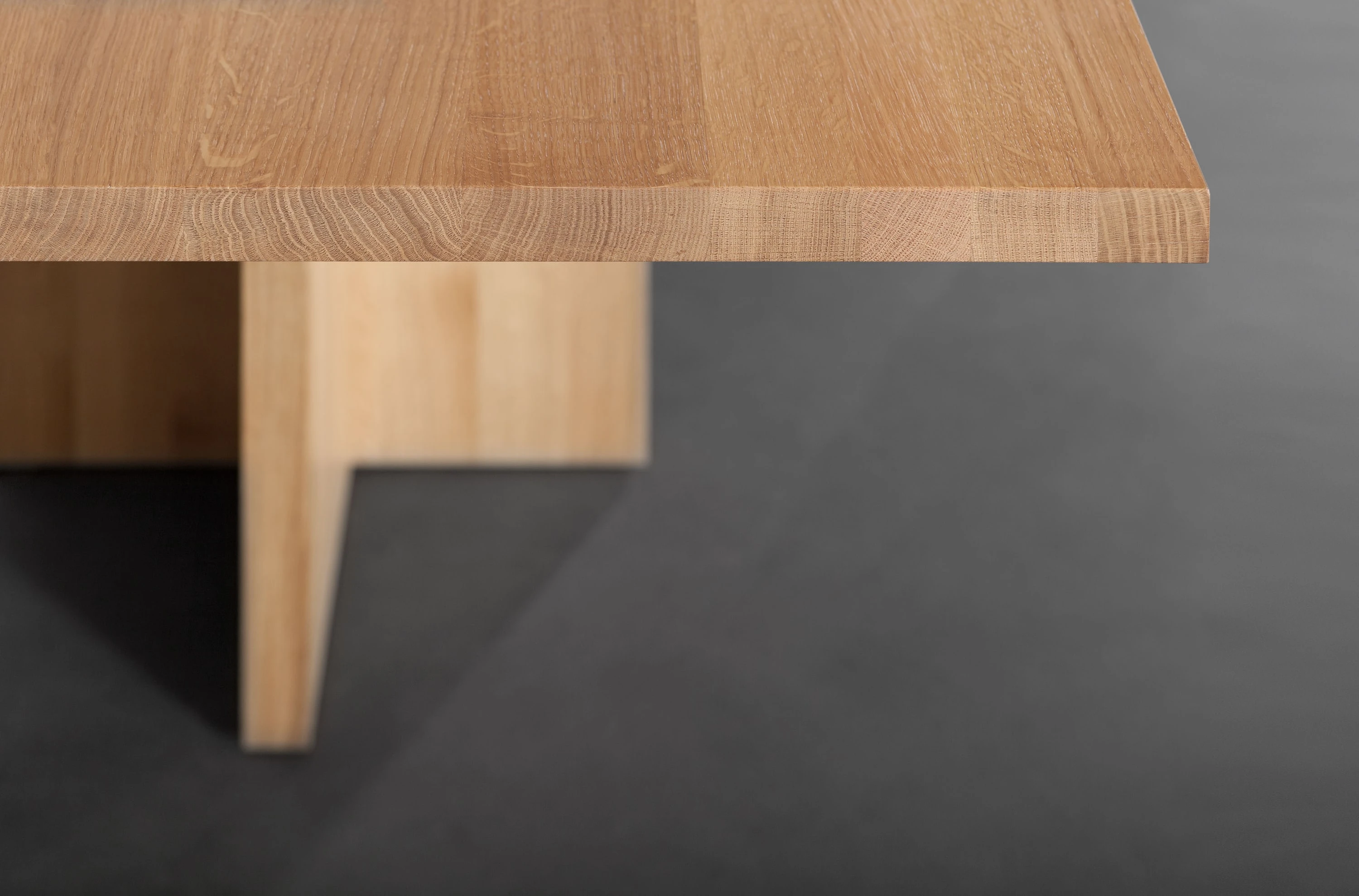 Nahaufnahme einer Tischecke aus Holz mit kreuzförmigem Fuss.