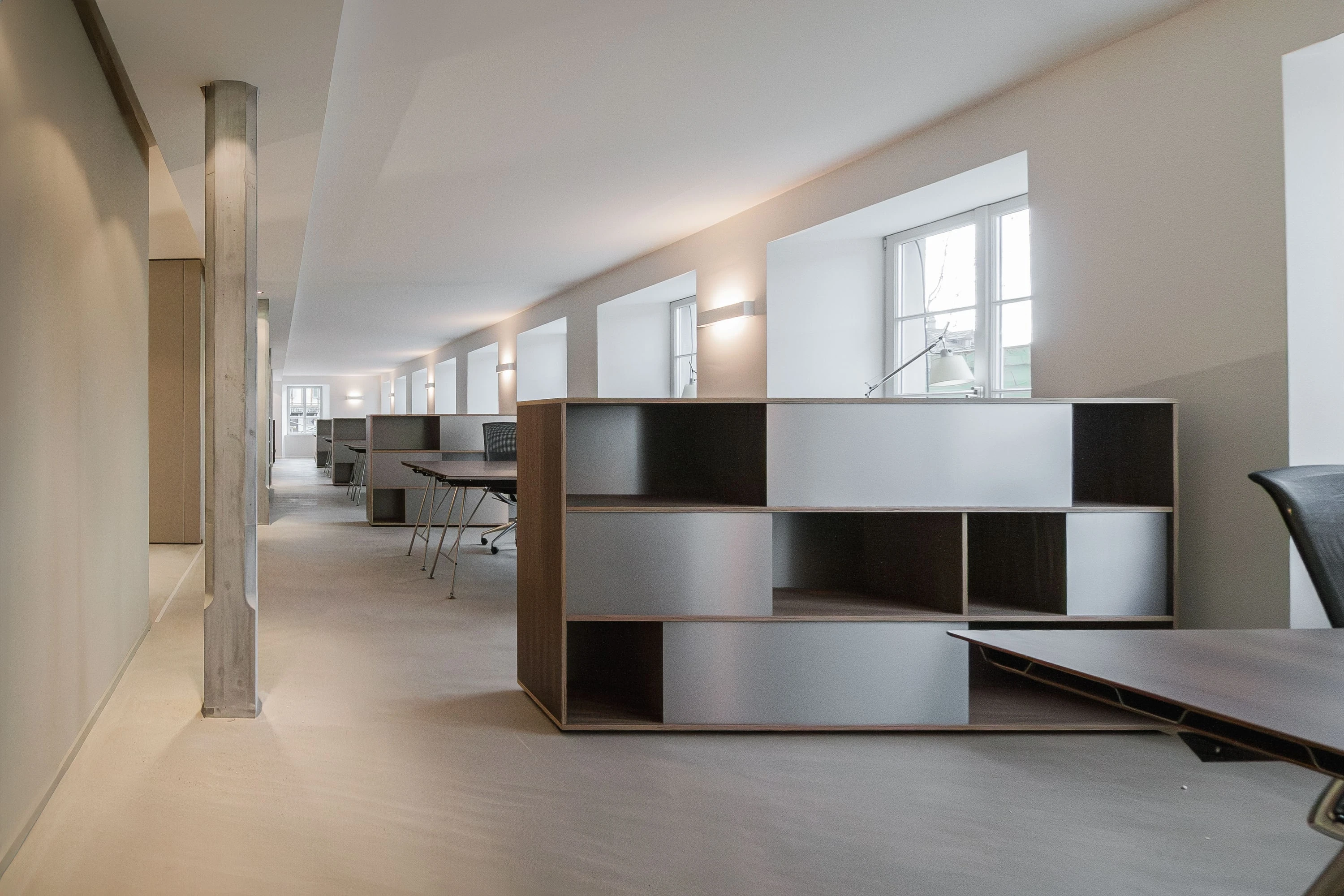 Lange Bürofläche mit Stützen und einem Highboard aus Nussbaum und Aluminium im Vordergrund.