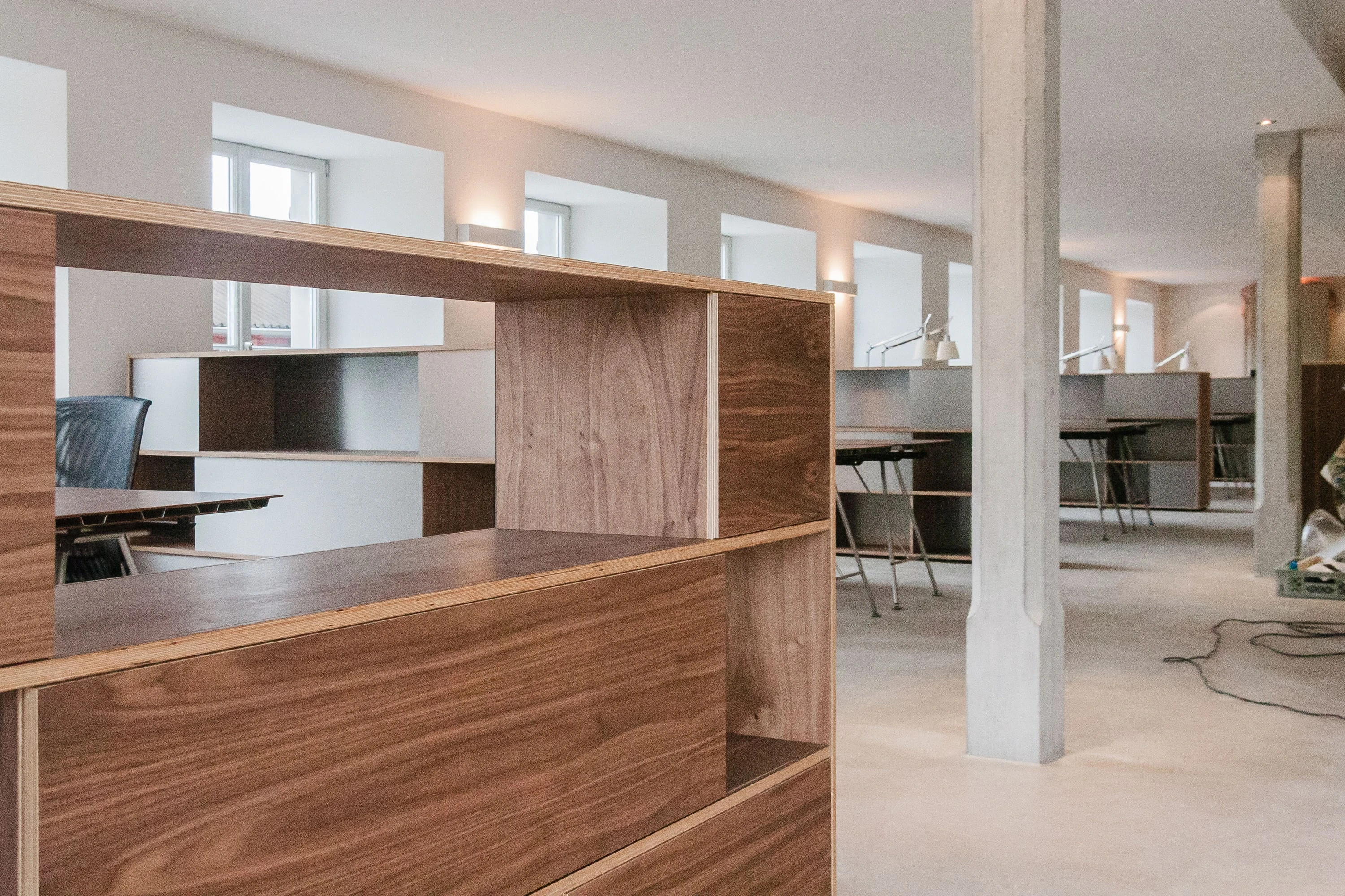 Nahaufnahme eines Highboards aus Nussbaum mit offenen Fächern in der Bürofläche.