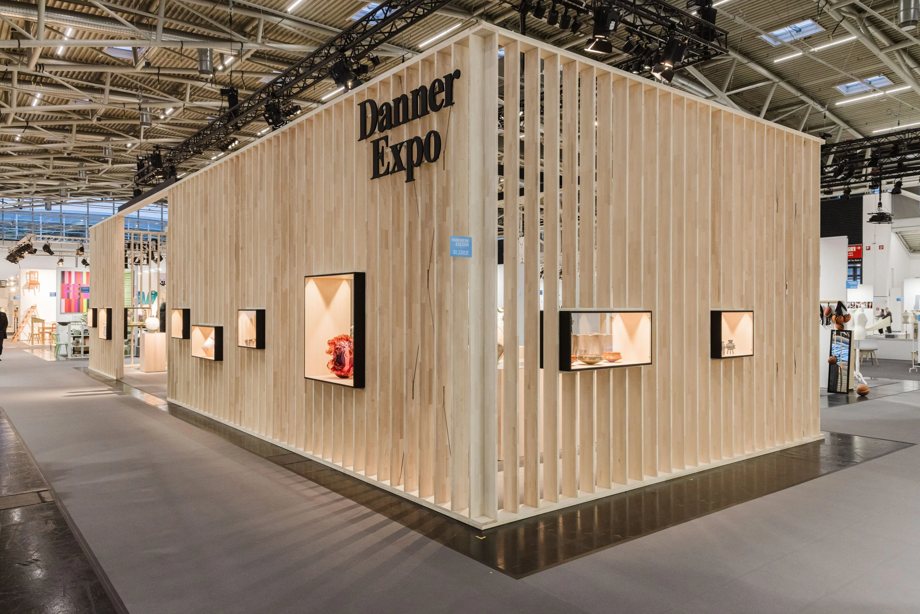 Ecke des Messestands mit dem Schriftzug Danner Expo und Lamellenwänden mit eingelassenen Vitrinen.