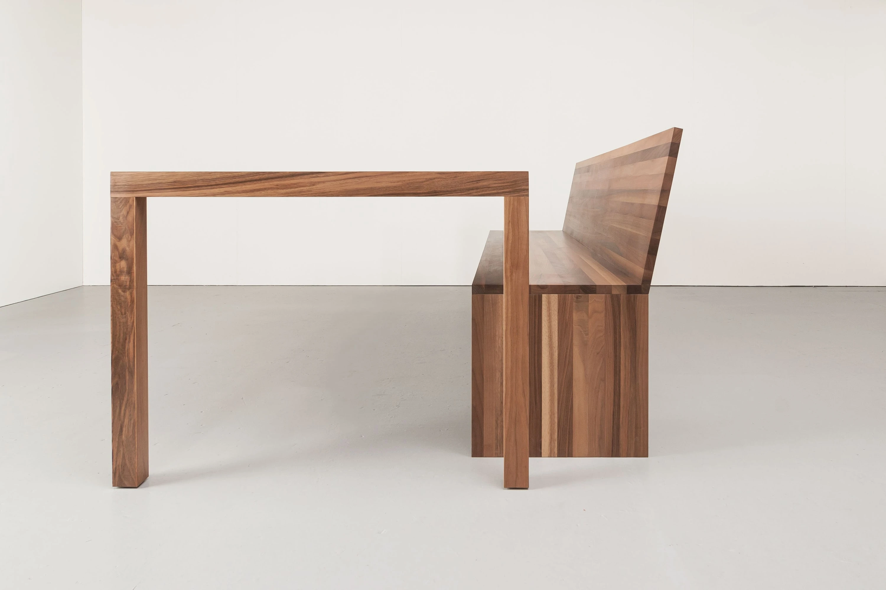 Tisch und Bank mit Rückenlehne aus Nussbaum in der Seitenansicht.