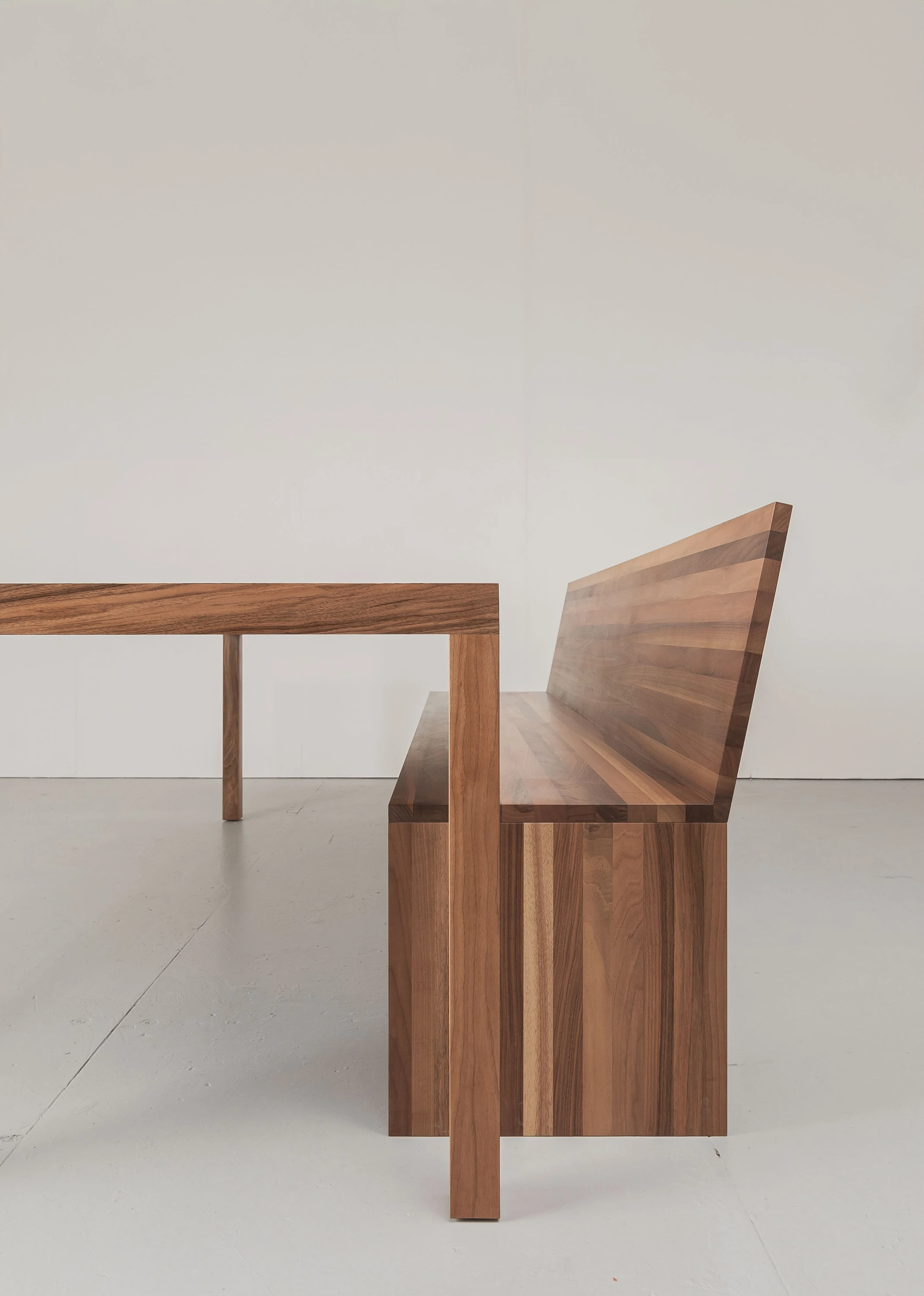 Tisch und Bank mit Rückenlehne aus dunklem Holz in der Seitenansicht.
