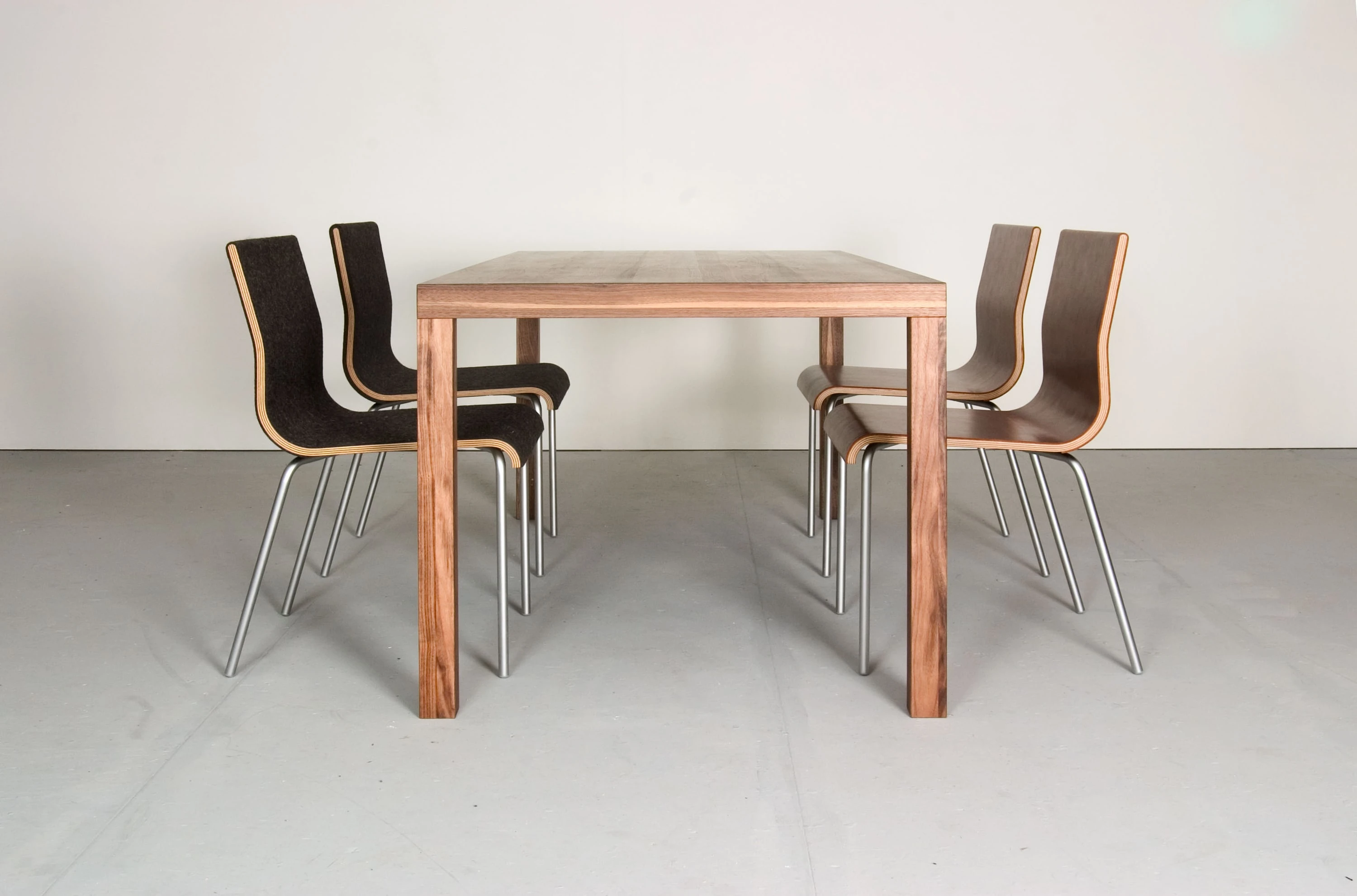 Tisch aus dunklem Holz in der Stirnansicht mit je zwei Stühlen auf beiden Seiten.
