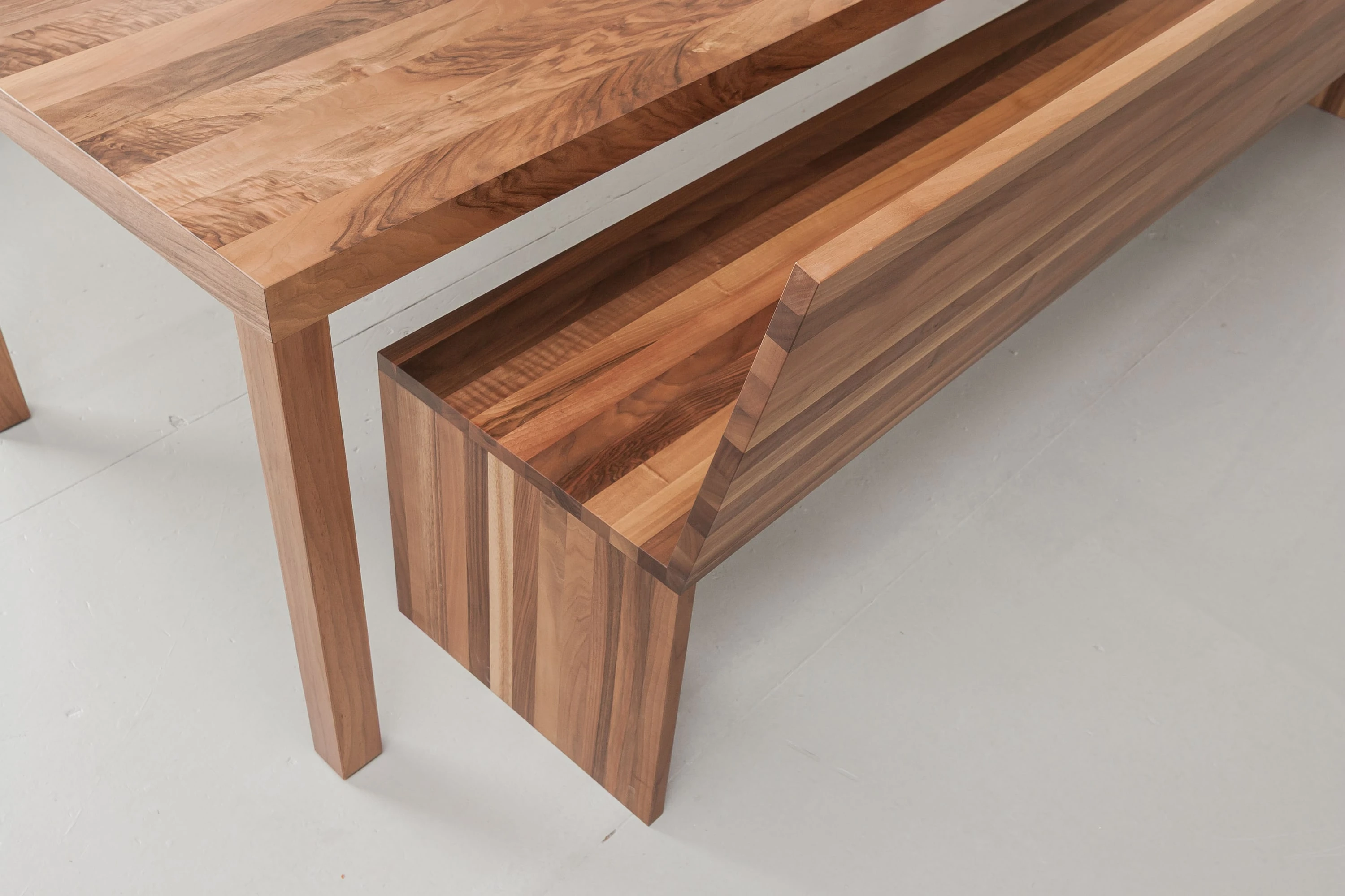 Tisch und Bank aus dunklem Holz, von schräg oben gesehen.