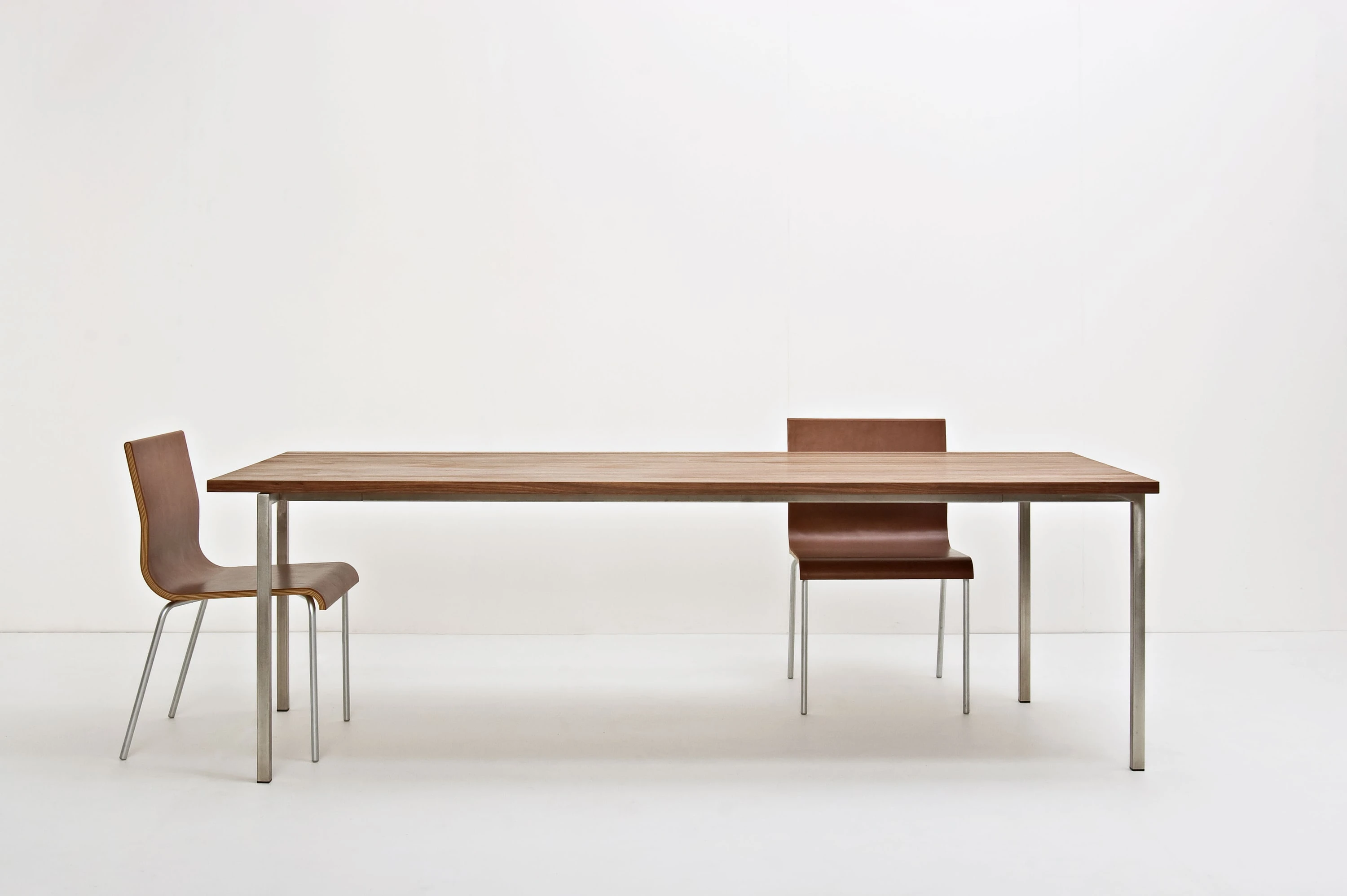 Tisch aus dunklem Holz auf Metallbeinen mit zwei Stühlen.