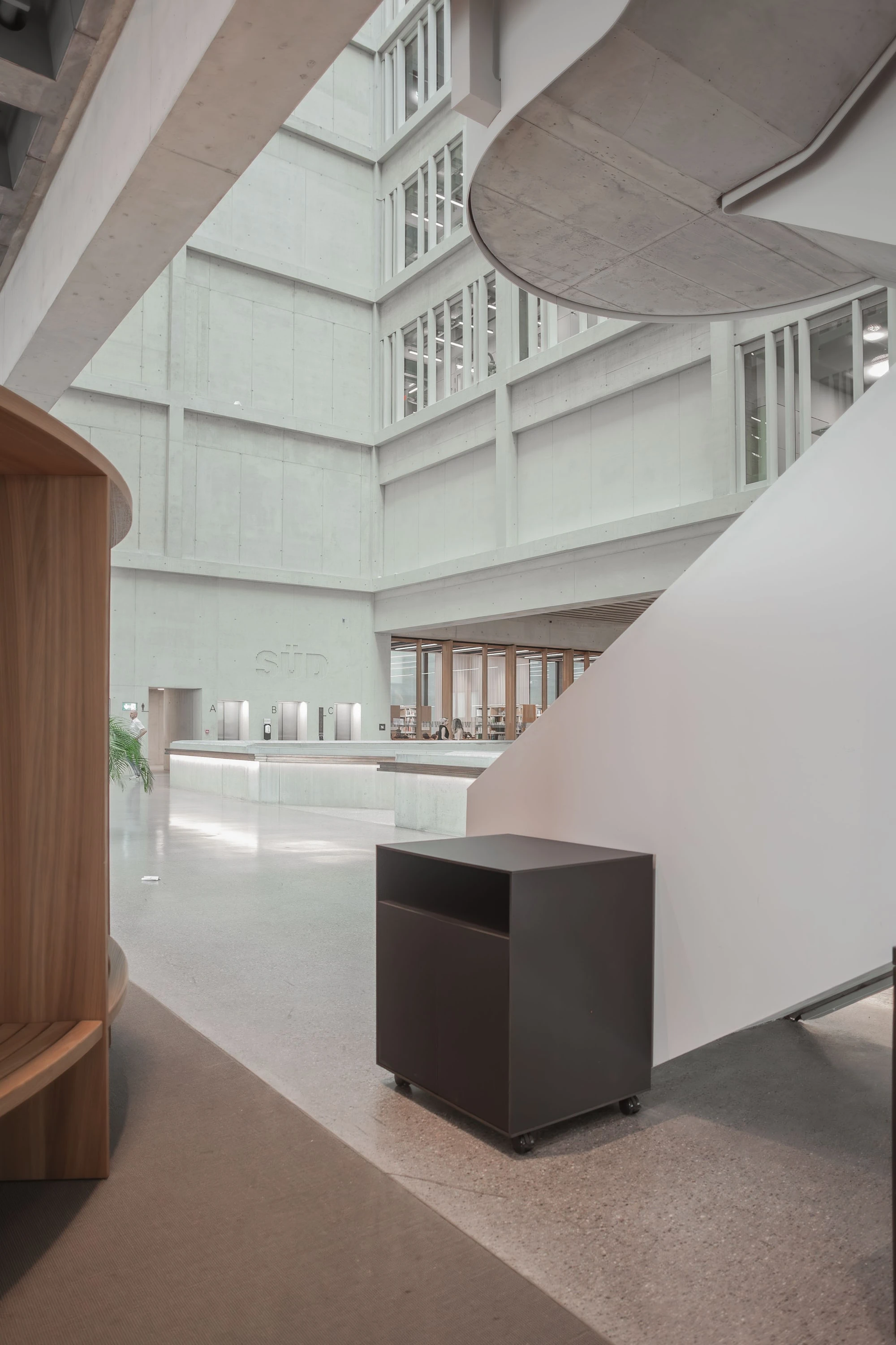 Dunkles Rollmöbel am Fuss einer geschwungenen Treppe im Atrium.
