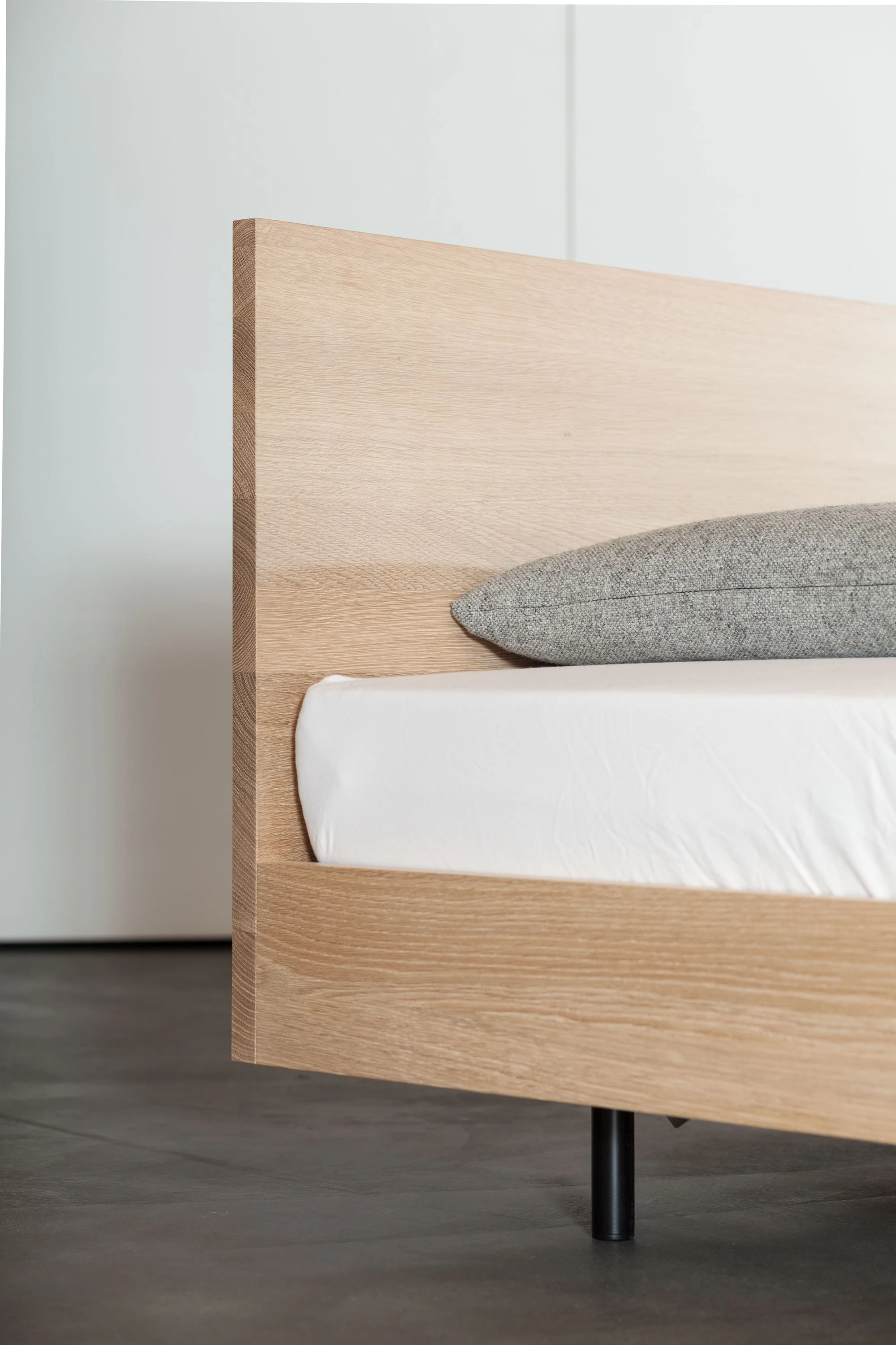 Kopfteil eines Bettes aus hellem Holz mit Kissen.