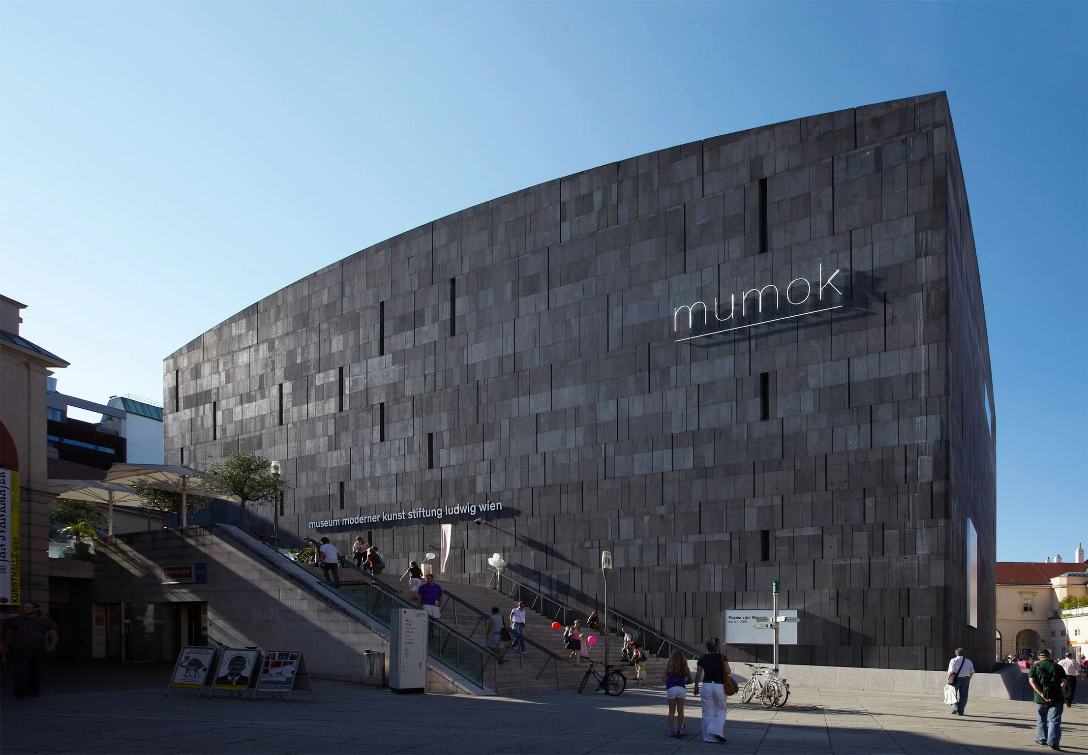 Aussenansicht des Museums mit dunkler Steinfassade und Freitreppe.