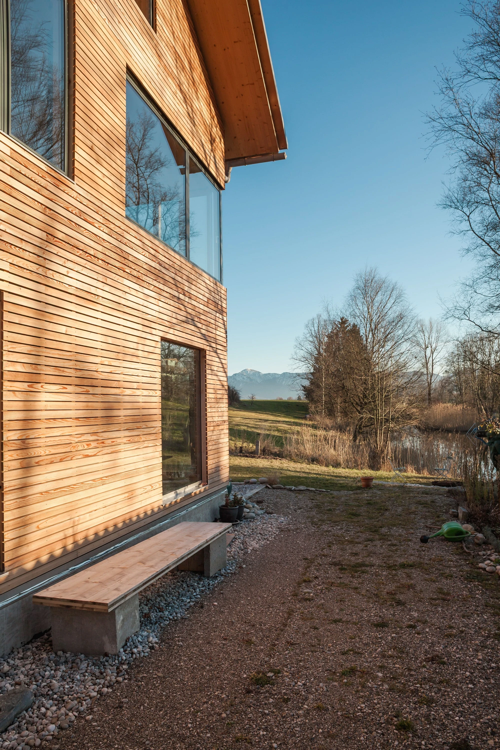 Holzfassade mit Bank an der Hauswand und Blick in die Landschaft.