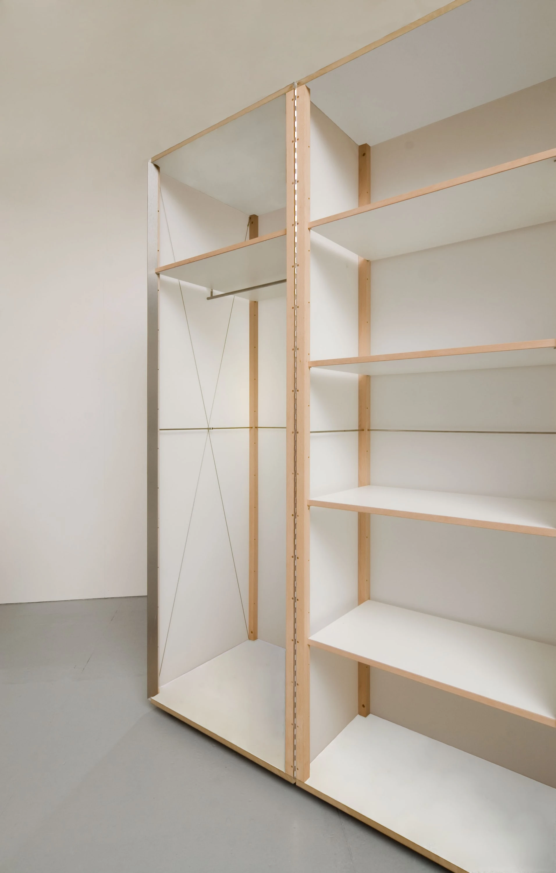 Offener Schrank mit Holzrahmen, Fachböden und heller Textilbespannung.