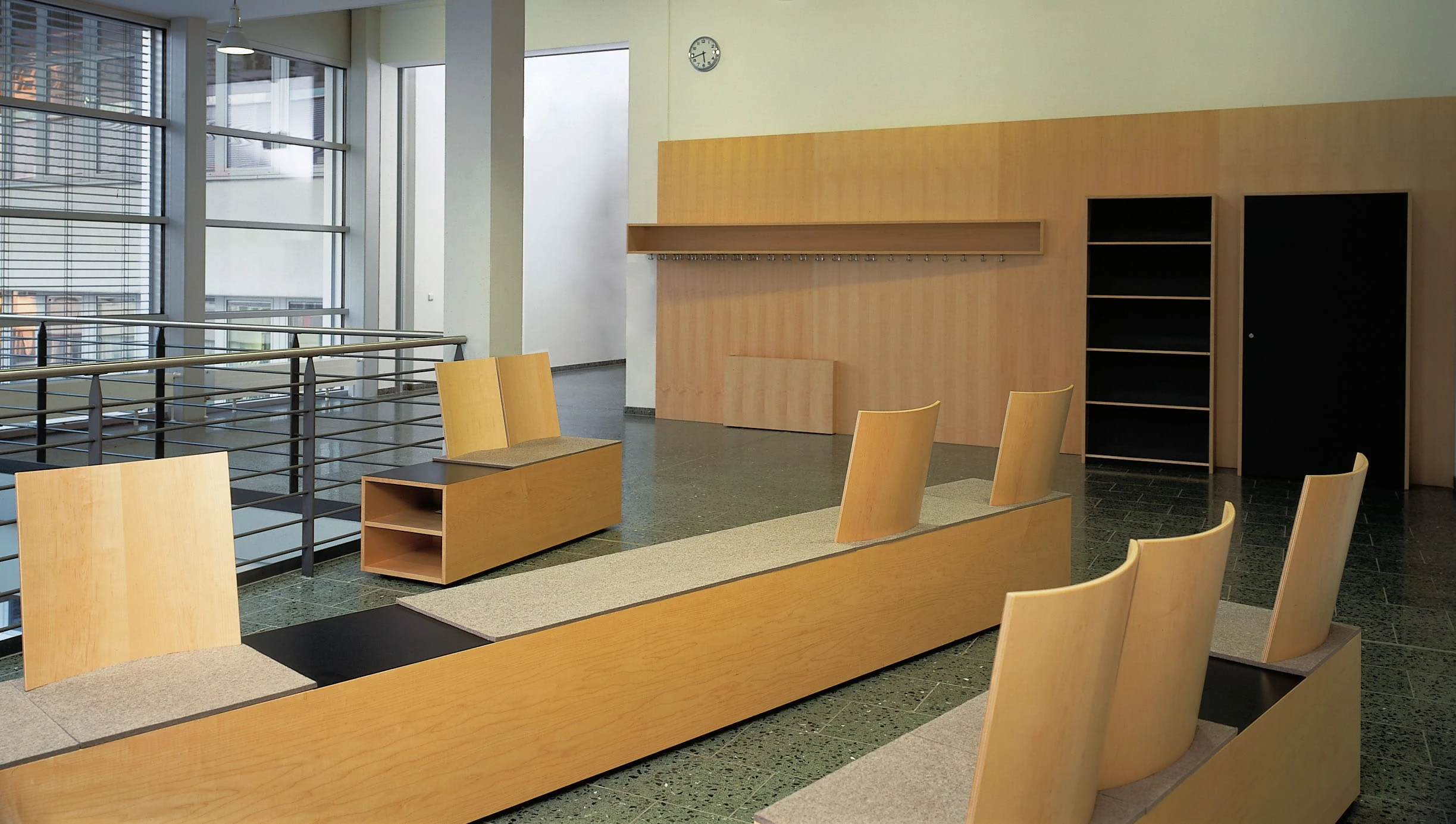 Foyer mit Sitzmöbeln und Wandelementen aus hellem Holz.