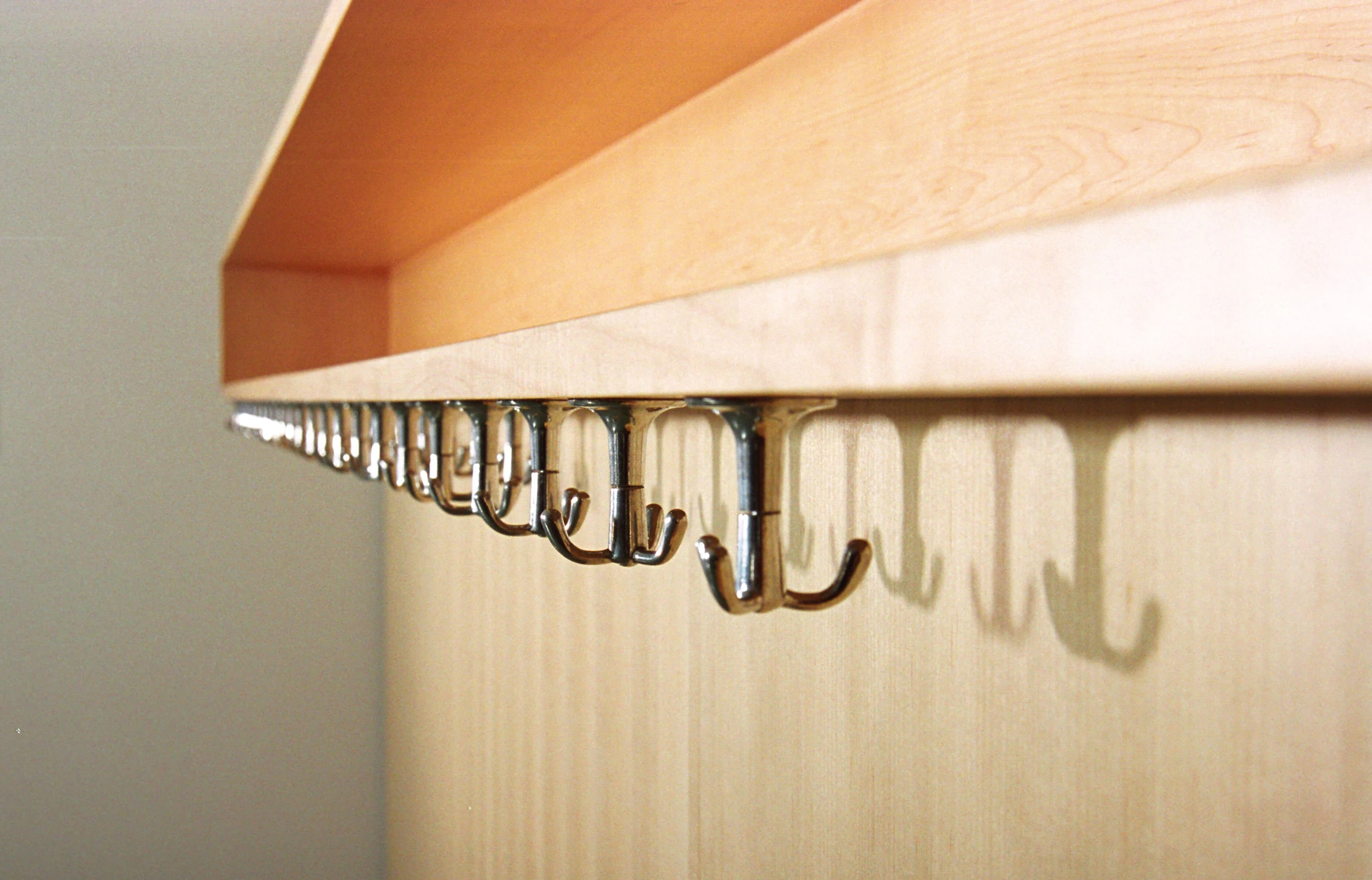 Detail einer Garderobe aus Holz mit einer Reihe von Haken.