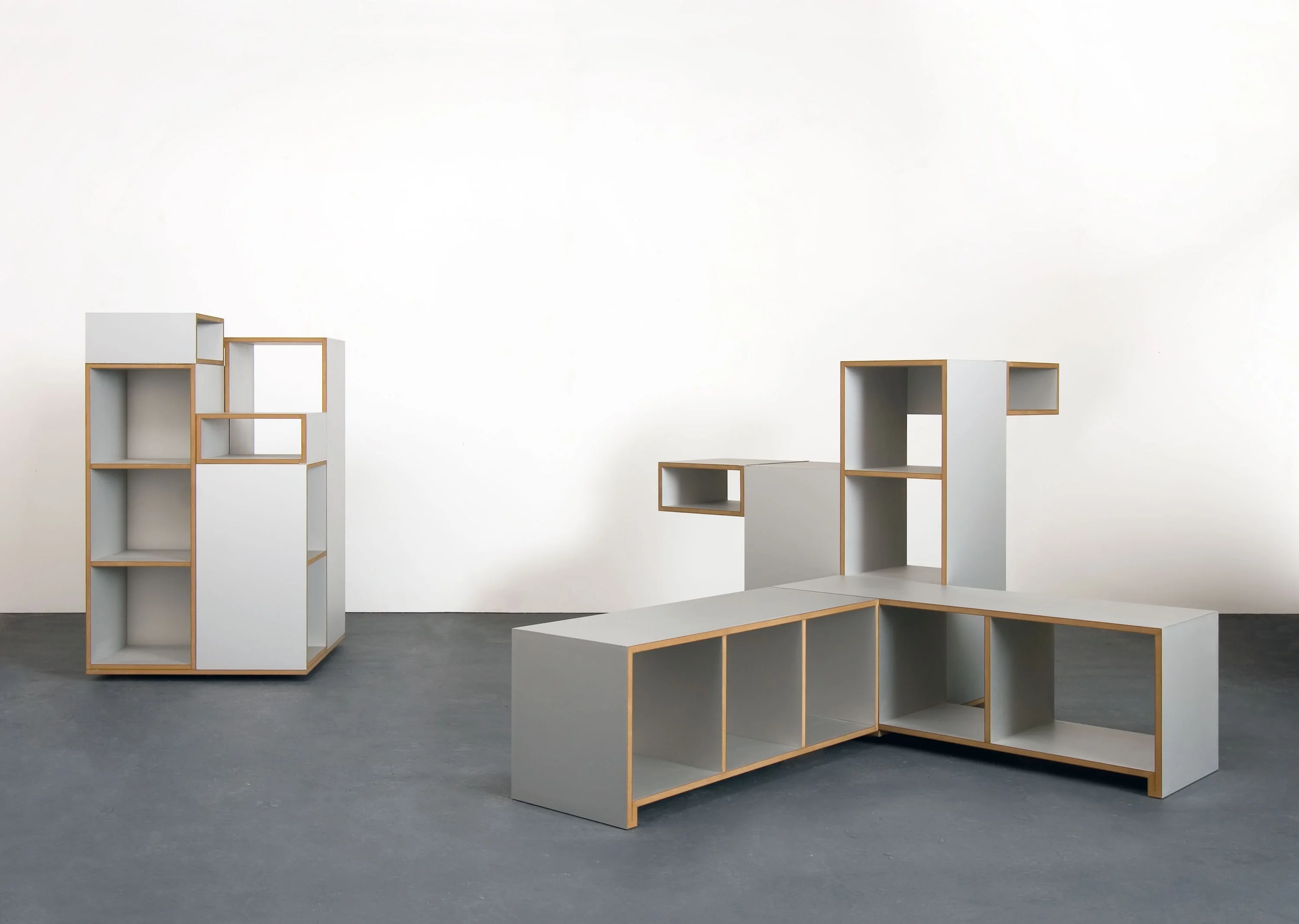Two furniture combinations of gray cubes with open compartments against a white wall.