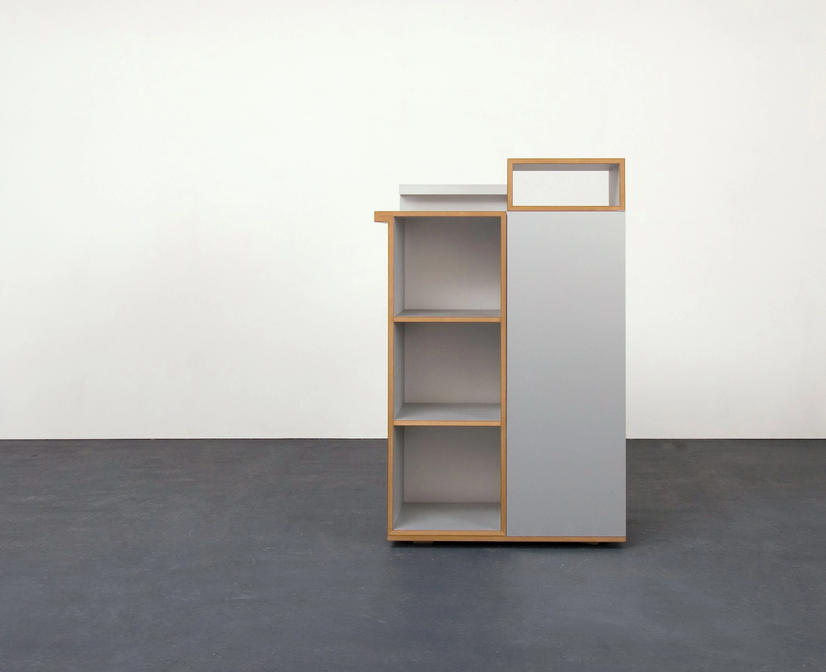 Shelf tower of gray elements with open compartments and a top module.