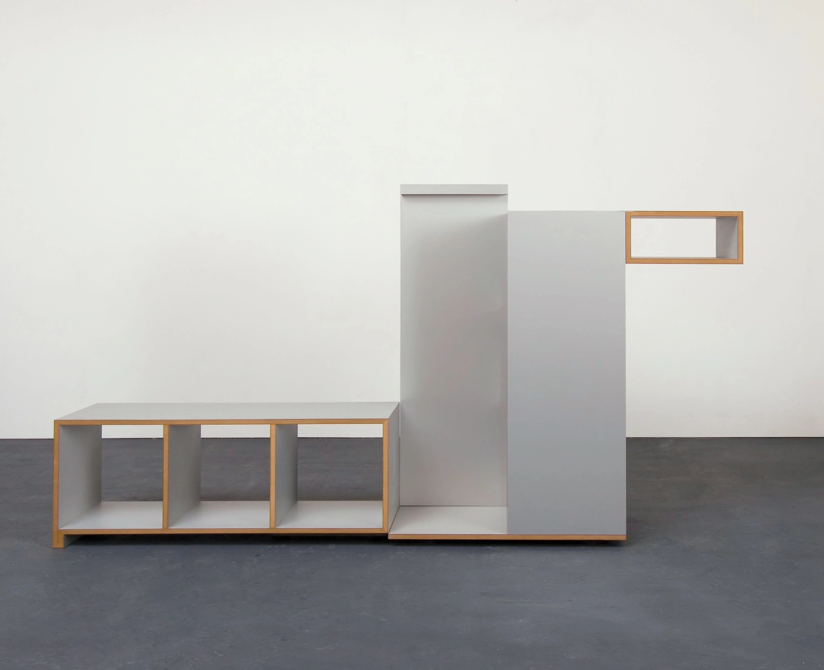 Low shelf and tall gray elements with a top box against a white wall.