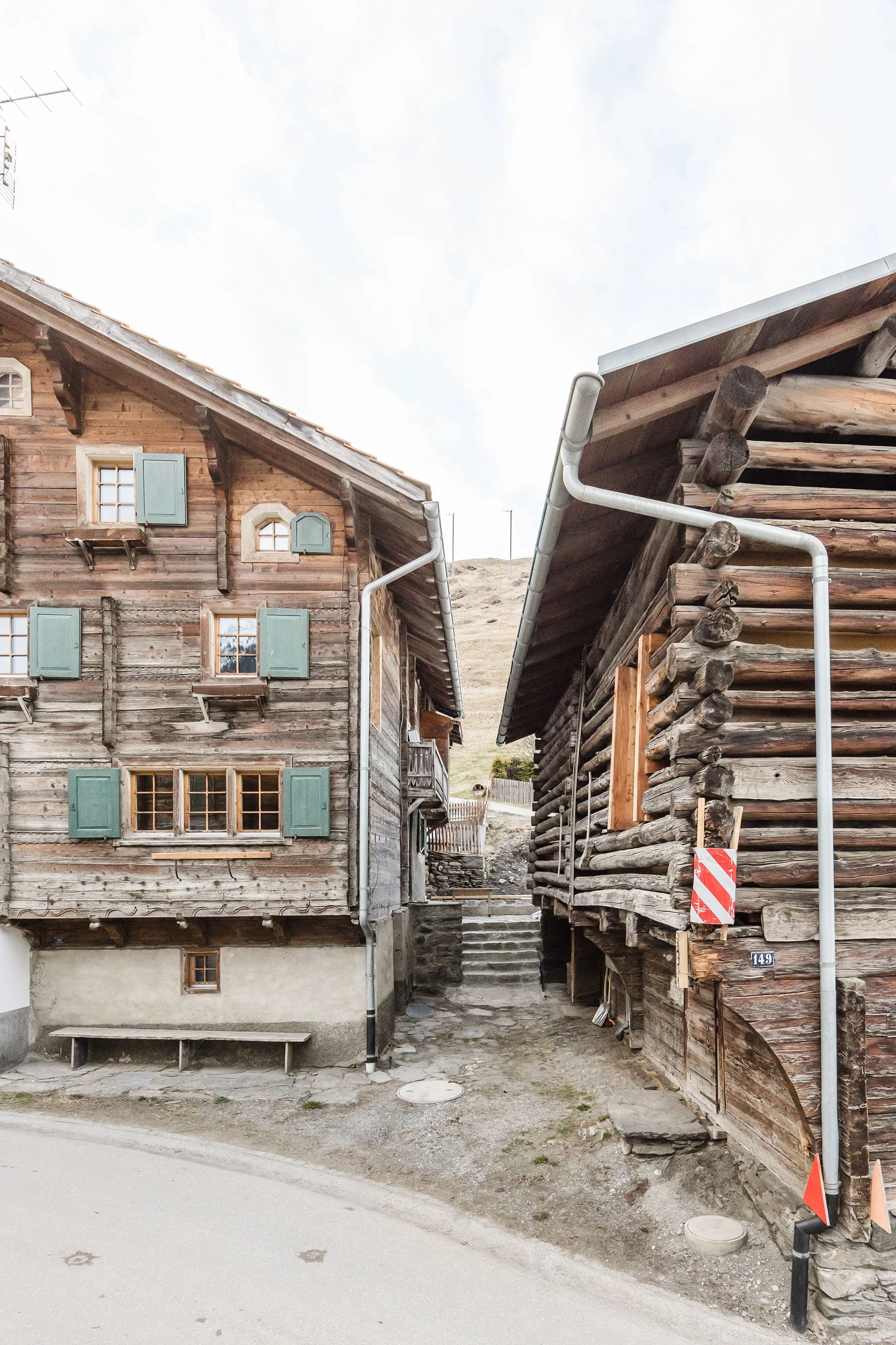 Gasse zwischen Strickbau und Stall mit Treppe im Hintergrund.