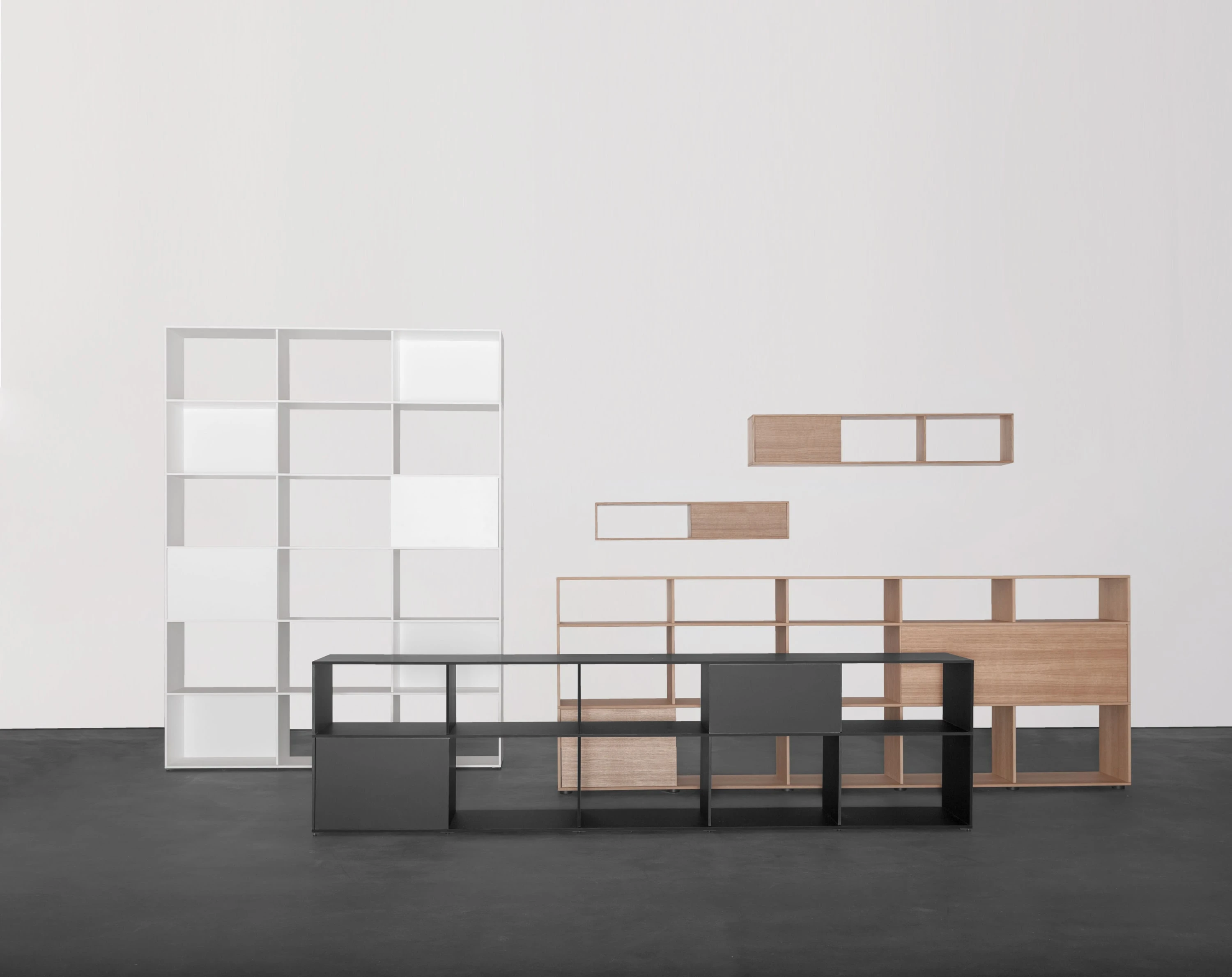 Hohes weisses Regal, schwarzes Sideboard, Highboard aus Eiche und Wandregale in einer Gruppe.